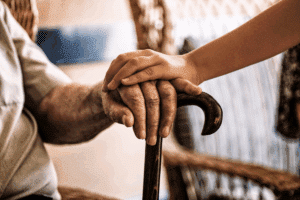a young child rests their hand on their grandparent's hand